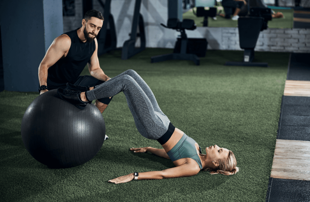 A woman performing nordic curls for hamstrings with a ball