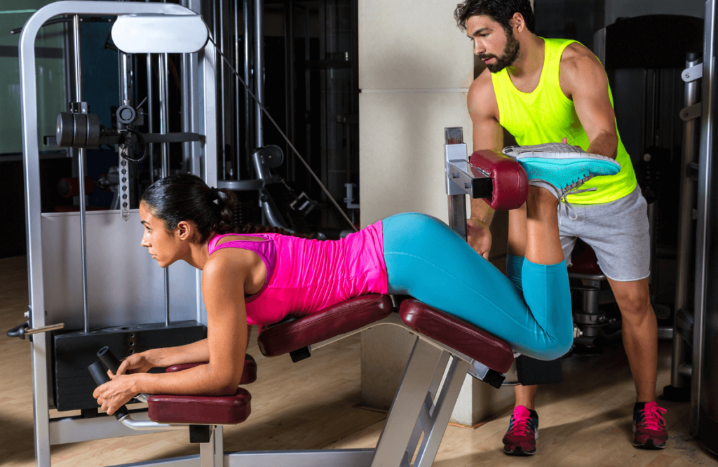 A woman performing nordic curls with her coach