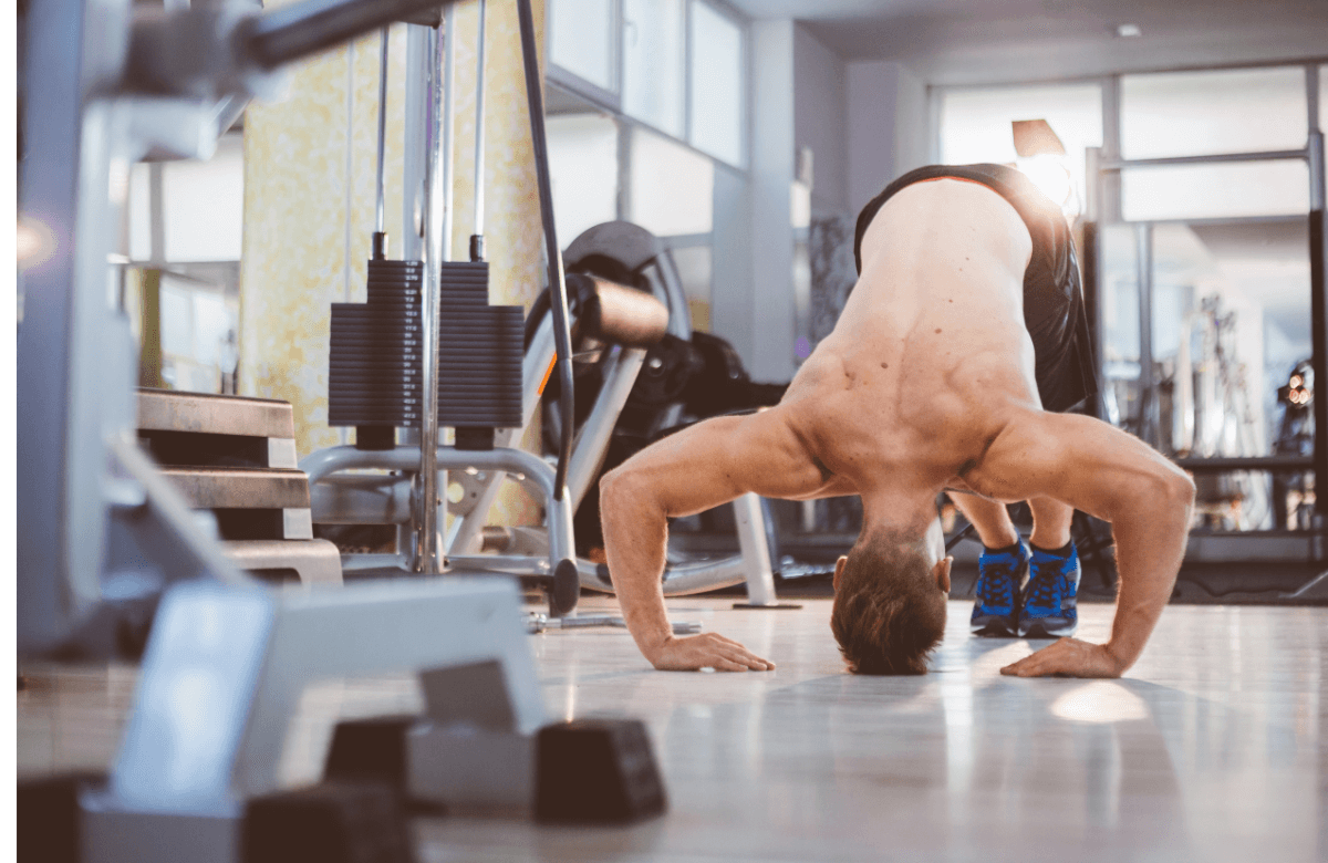 Un homme réalise une pike push-up en salle de musculation