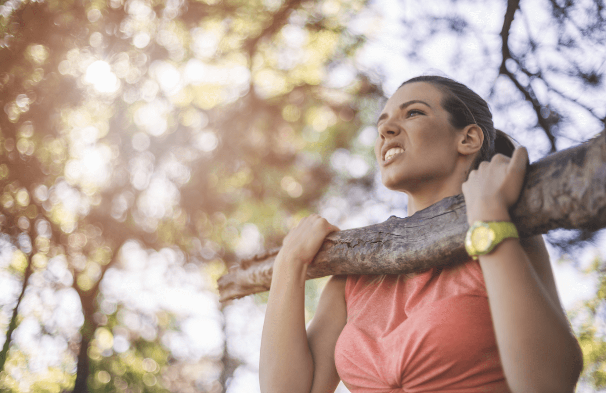 Un femme réalise une traction sur une branche, un exercice biceps sans matériel