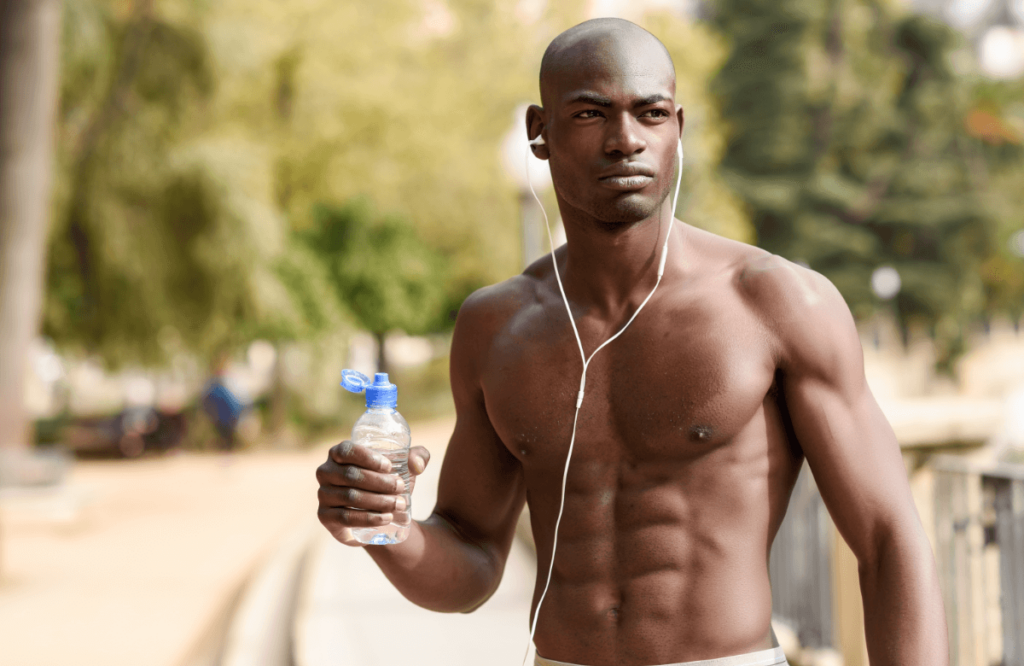 un hombre negro musculoso bebe agua al aire libre