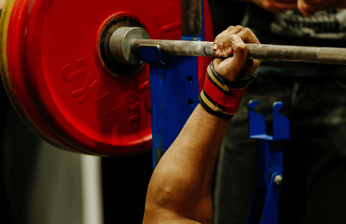 A strong man lifting a barbell using the best wrist wraps