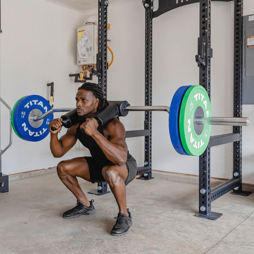 An athlete using a safety squat bar in front of a squat rack