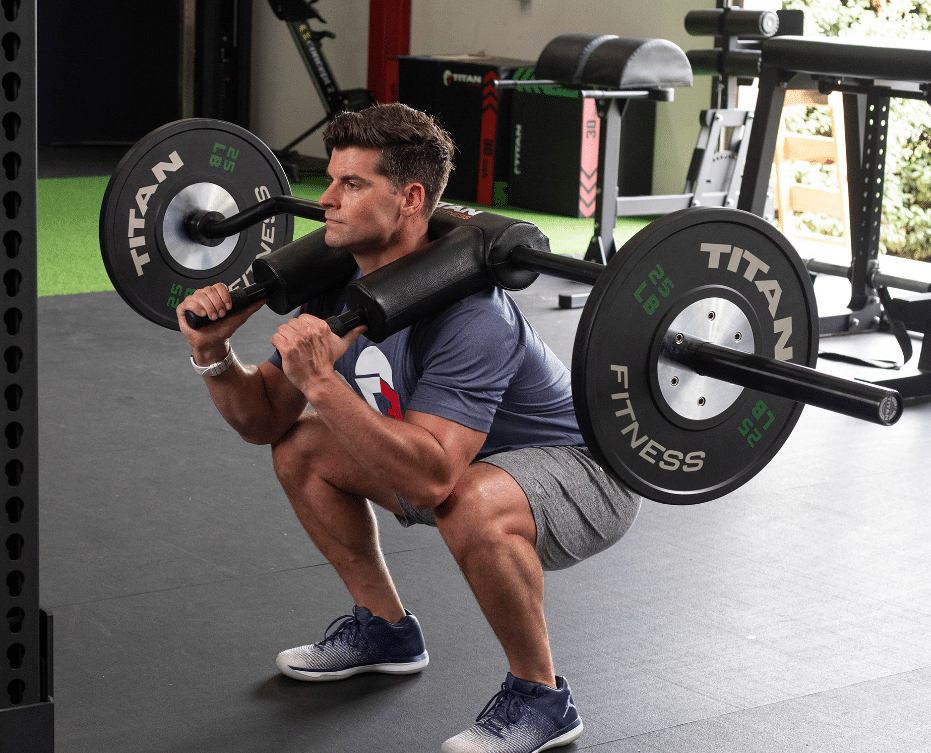 A man using a safety squat bar at the gym with Titan plates