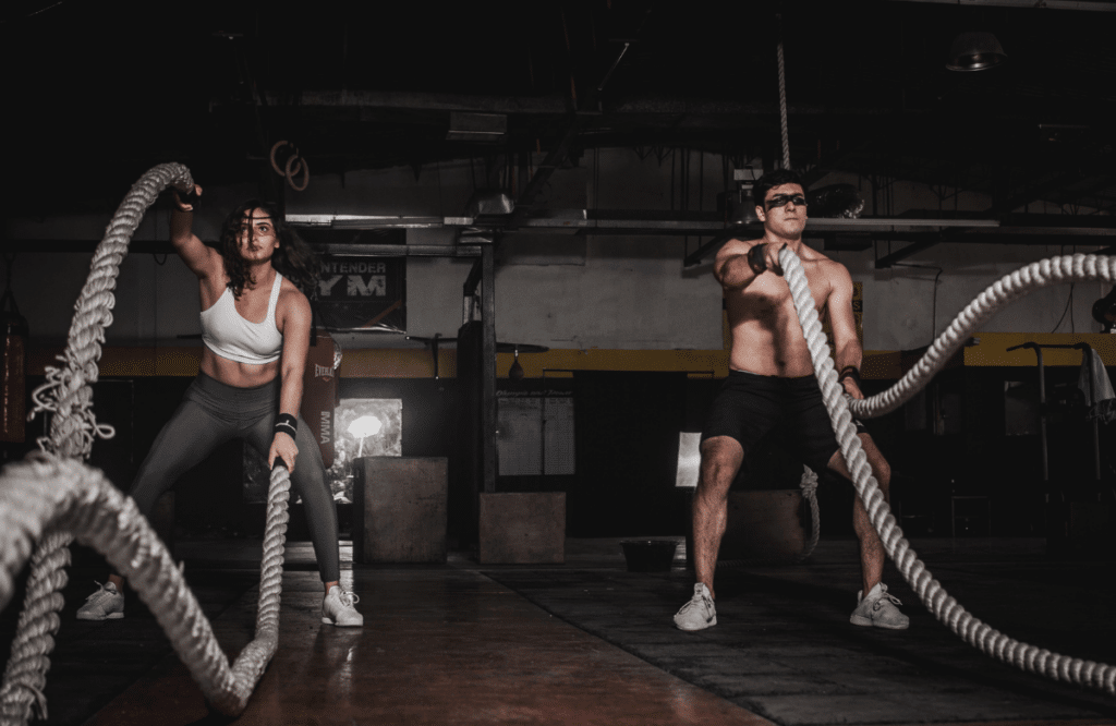 A man and a woman using ropes during their full body workout session