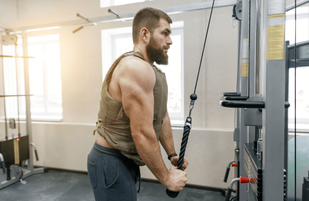 A strong man using the best weighted vest with a cable machine