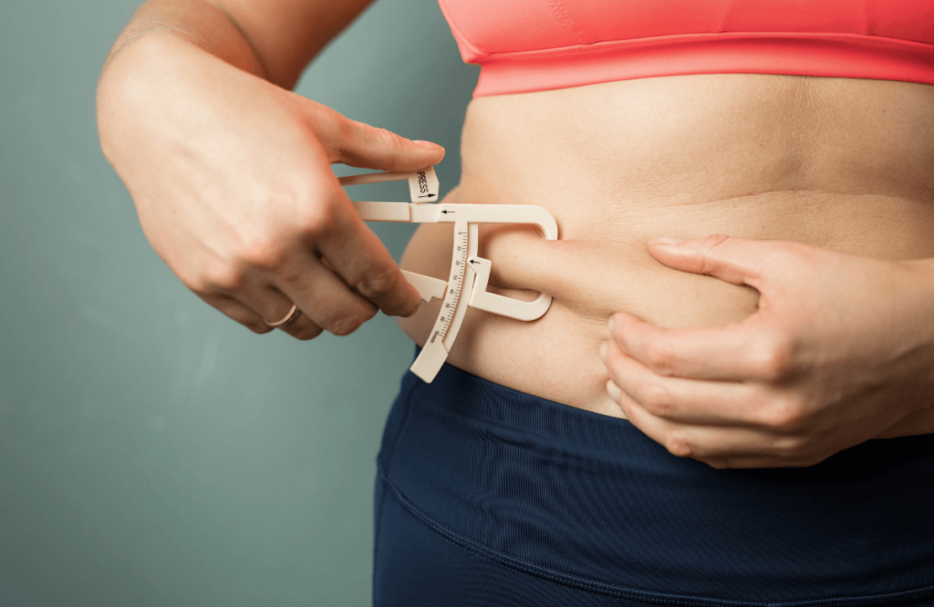 A woman measuring her belly fat before doing the best exercise to burn belly fat