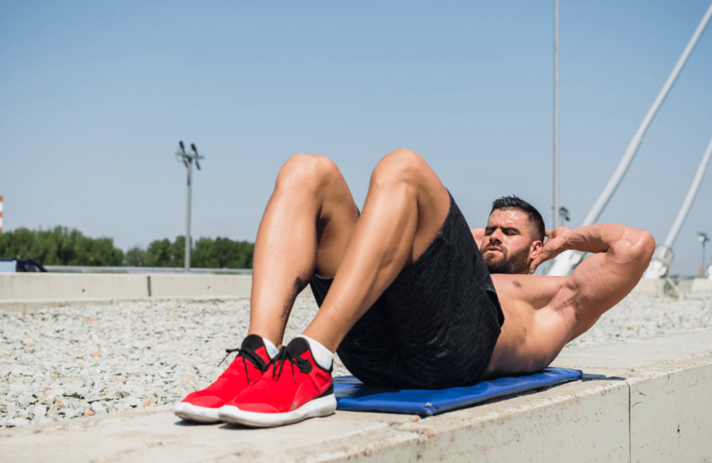 A man doing crunches outside in order to get a six-pack