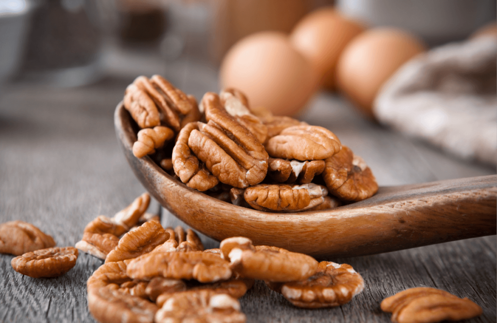 A wooden spoon filled with pecans