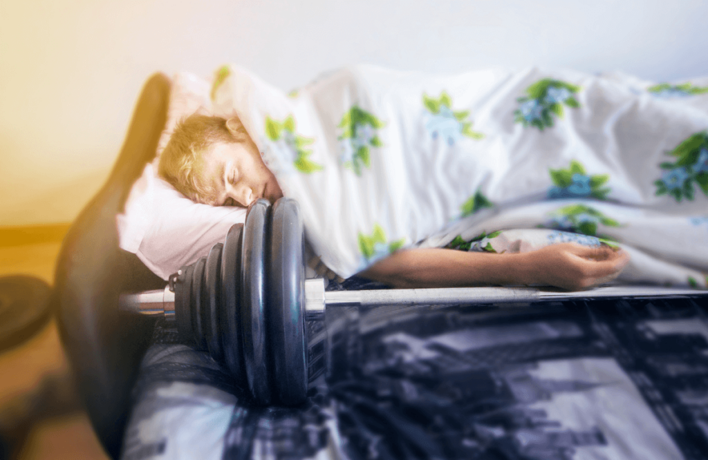 A man sleeping with his barbell to illustrate the fact that sleeping is extremly important for your workout plan