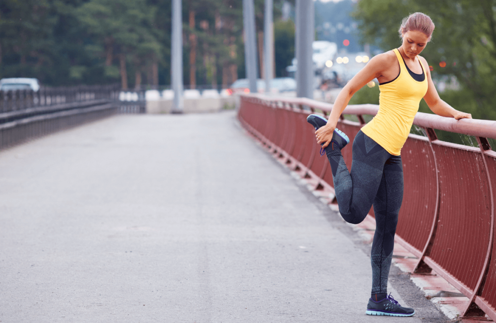 A woman stretching her quads on a bridge after her footing