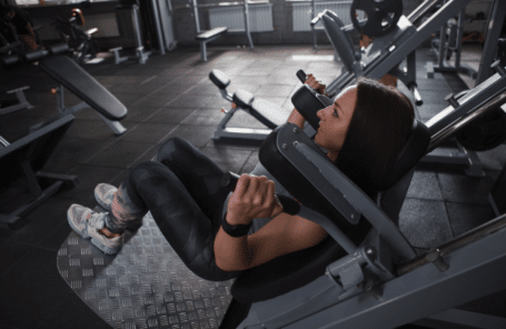 una mujer hace sentadillas hack en un gimnasio