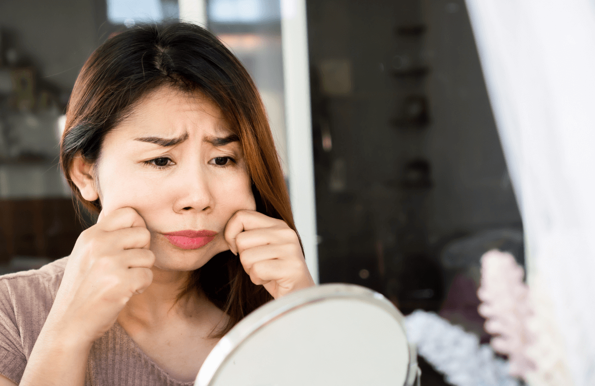 A worried woman wondering how to lose face fat