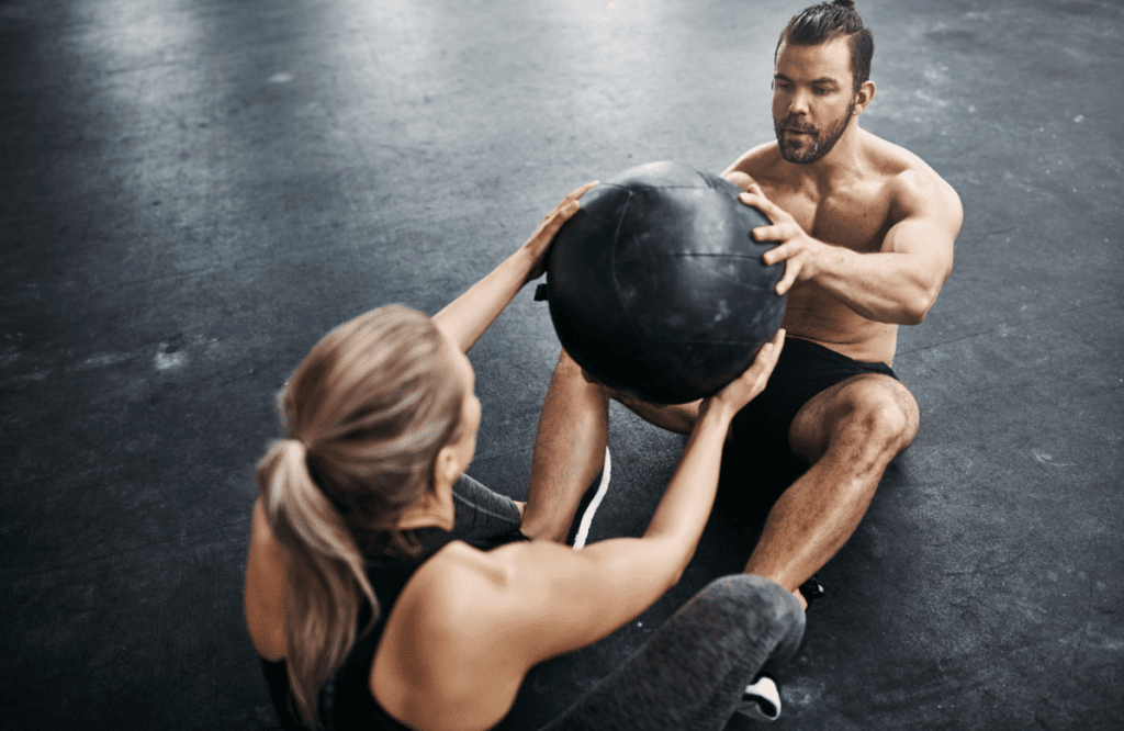 A man and a woman using a medicine ball during their core exercises