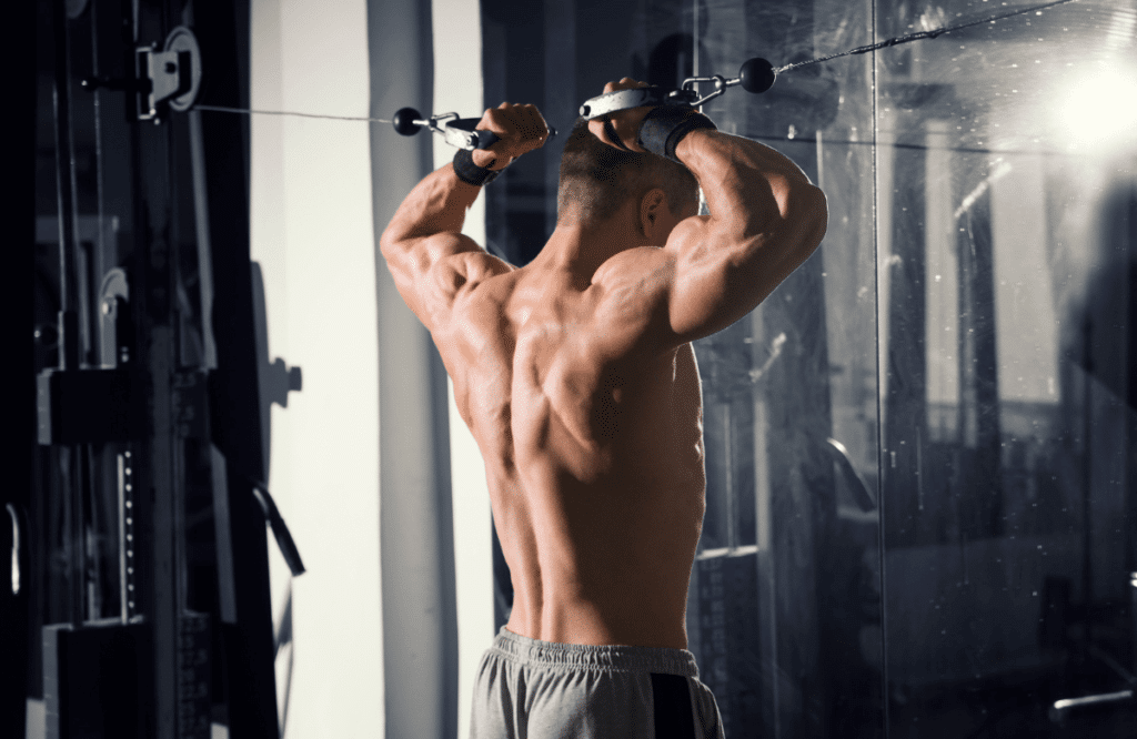 A muscular man doing bicep and tricep workouts using a cable machine