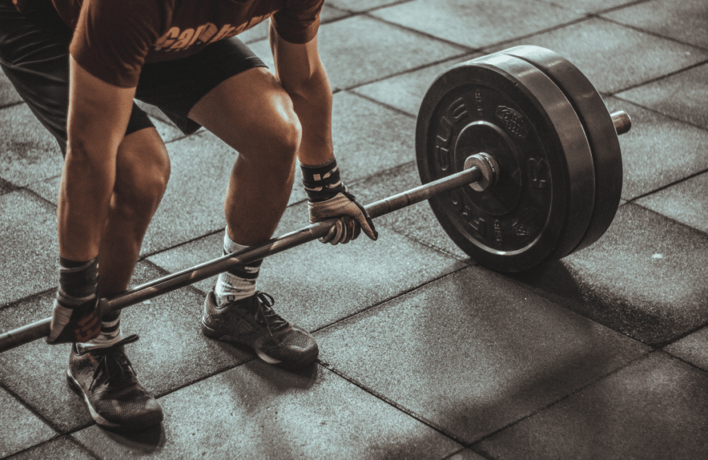 A strong man wearing the best weightlifting shoes and gloves