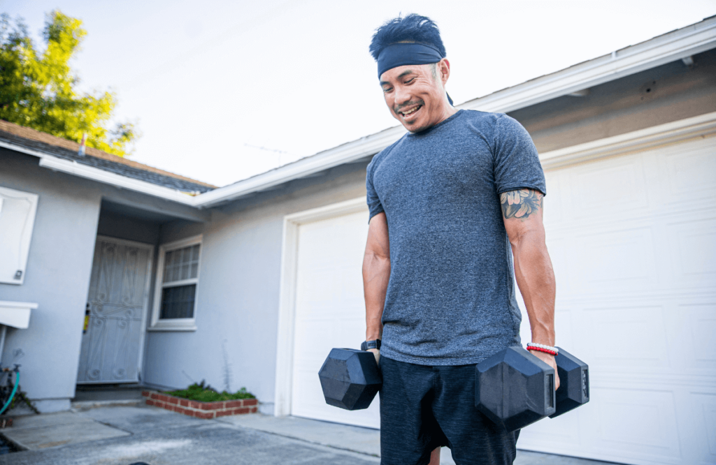 A man doing shoulder shrugs using dumbbells at home