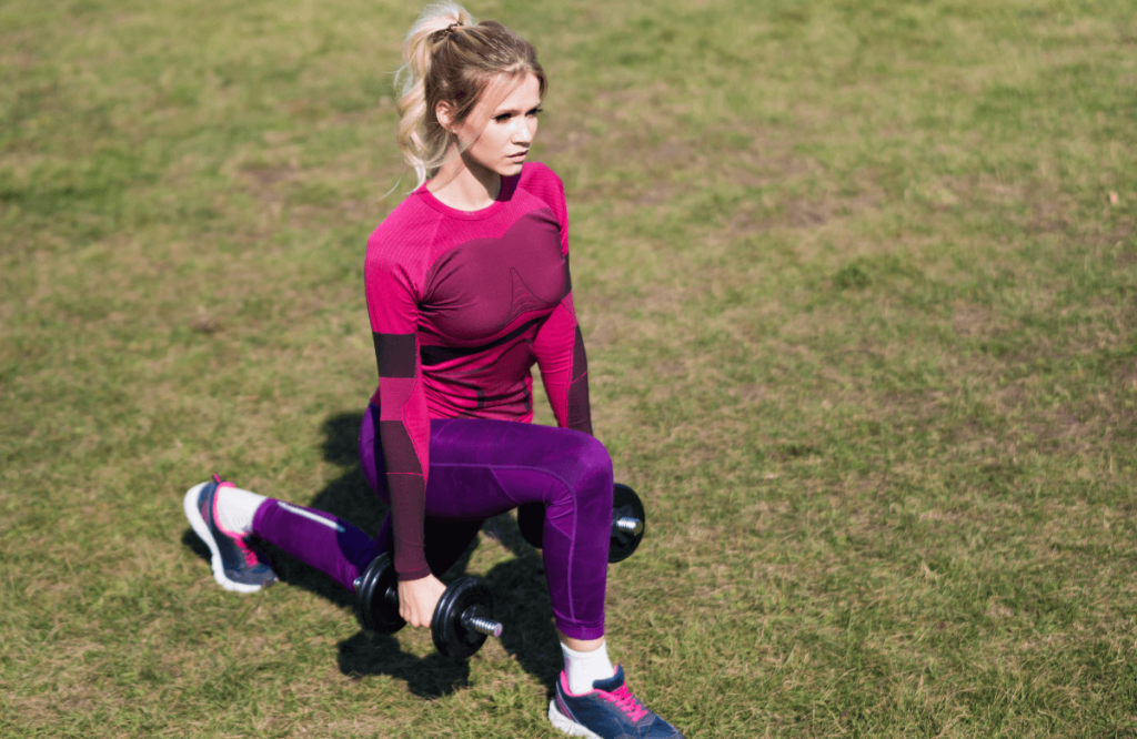 A woman doing leg workouts with dumbbells outside