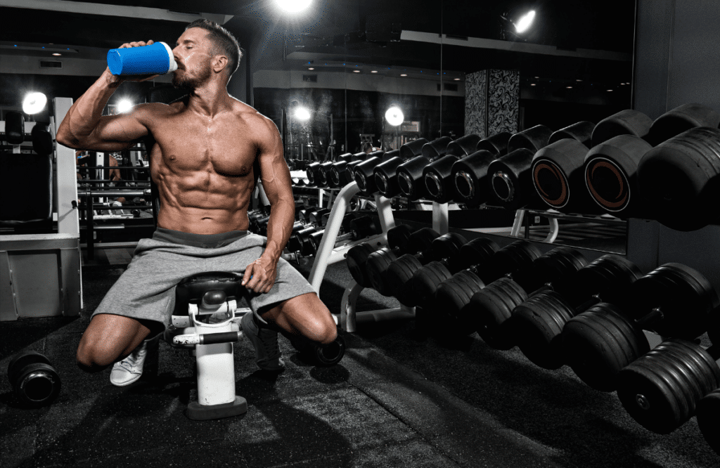 A strong man at the gym drinking a protein shake to improve his weight gain