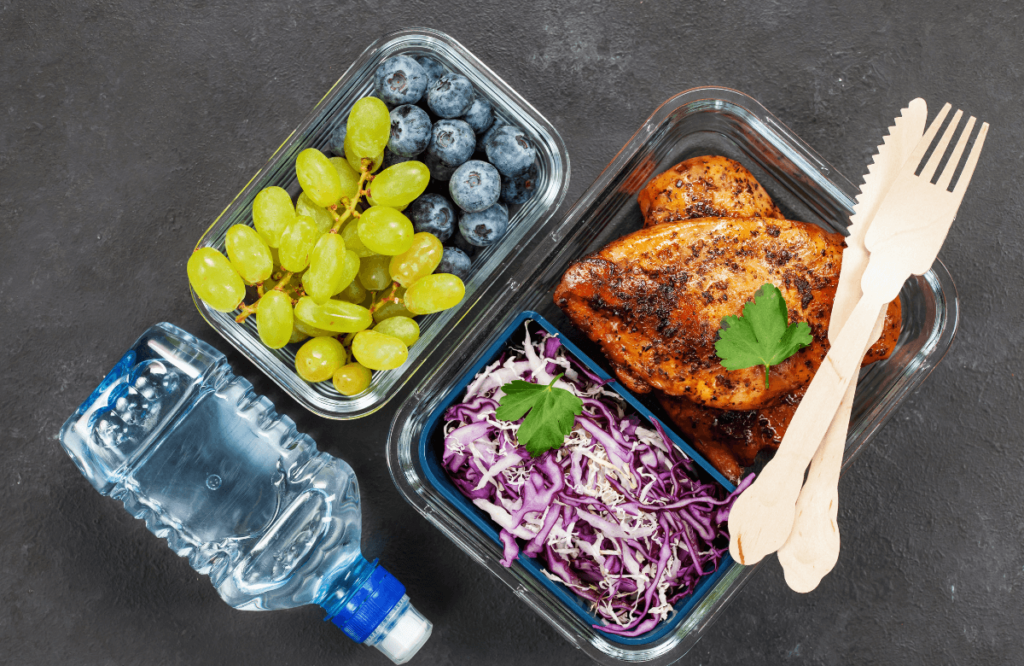 A meal prep with chicken, cabbage, blueberries and grapes