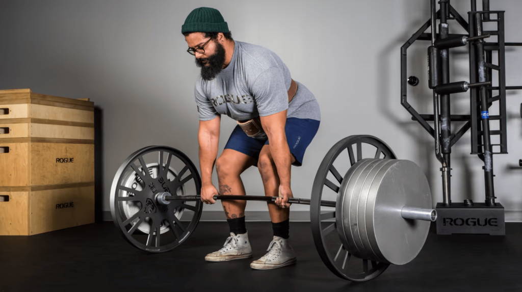 A man does a deadlift wearing converse