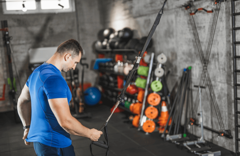 Man doing TRX Suspension straps overhead squats exercise. Flat