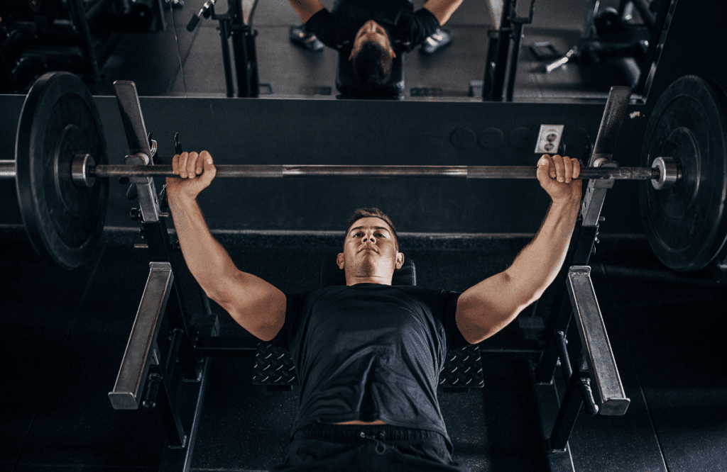 A muscular man does a wide grip bench press