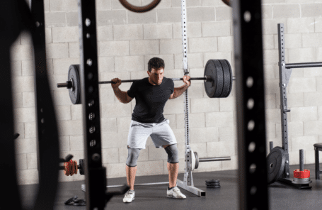A man does a back squat in a gym