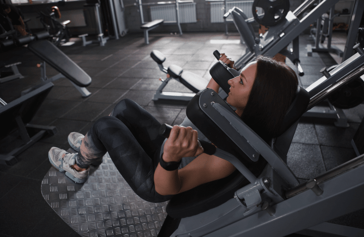 A woman does hack squats in a gym