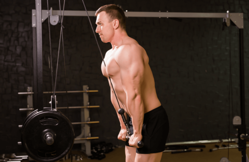 A man does triceps pushdown in a gym