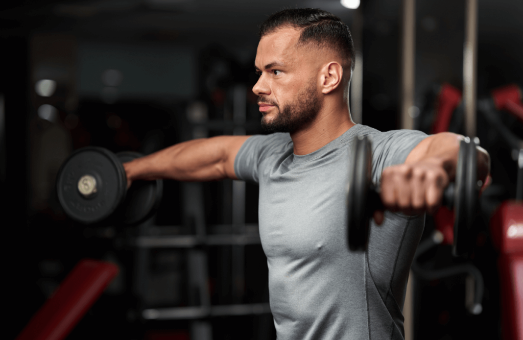 A man does lateral raises in a gym