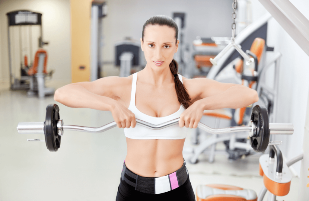 A girl does upright rows with a EZ bar