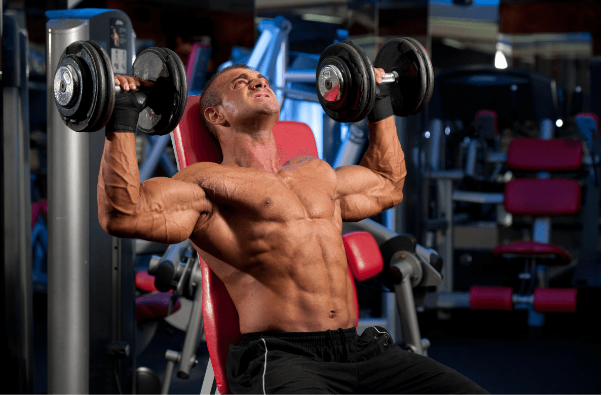 A man does shoulder presses in a gym