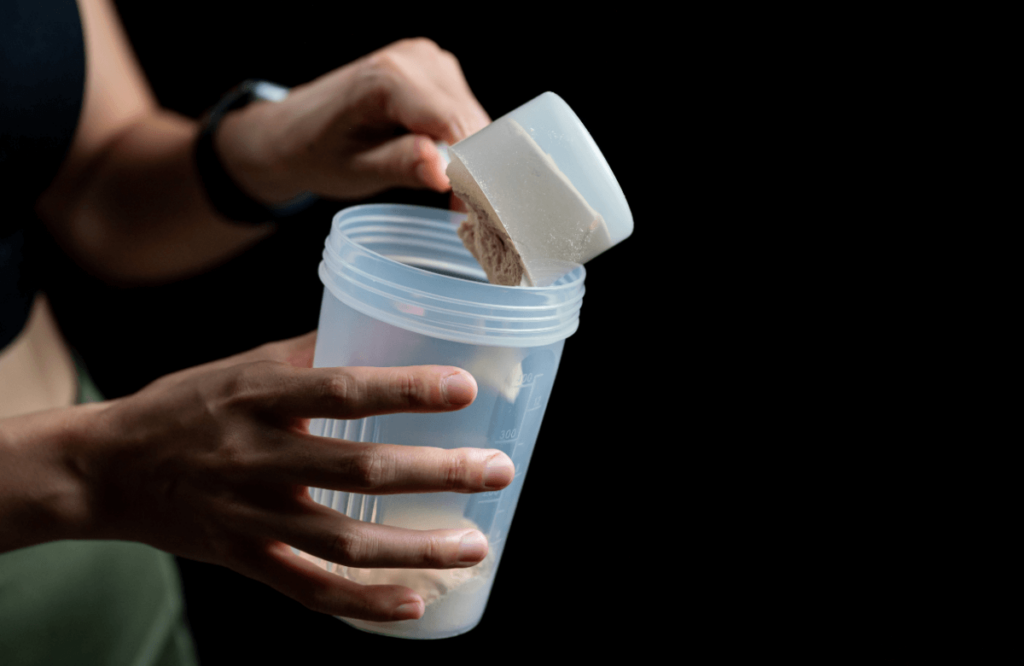 A woman pours creatine powder into a bottle