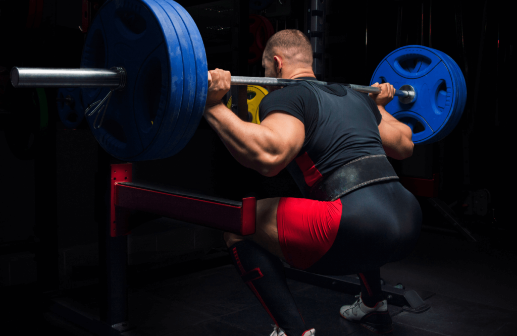 Muscular man does squats in a gym