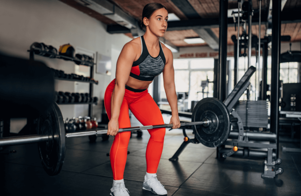 A woman does a power clean in a gym