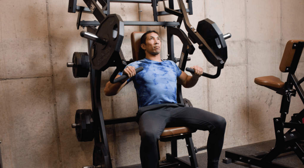 A man does machine press in a gym