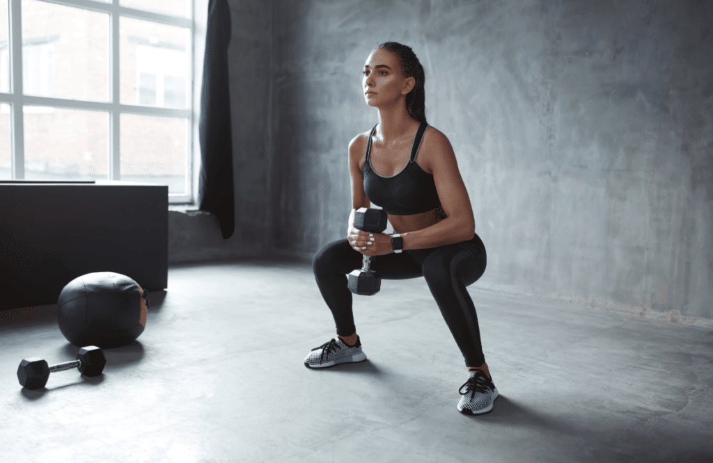 A woman does a dumbbell goblet squat