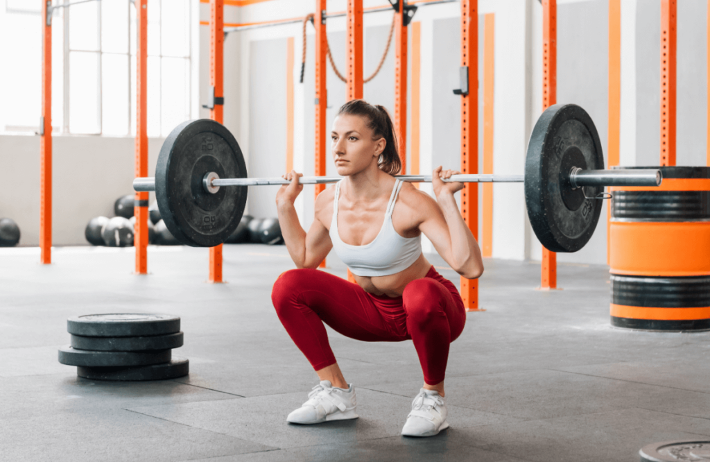 A woman does a barbell squat in a crossfit gym