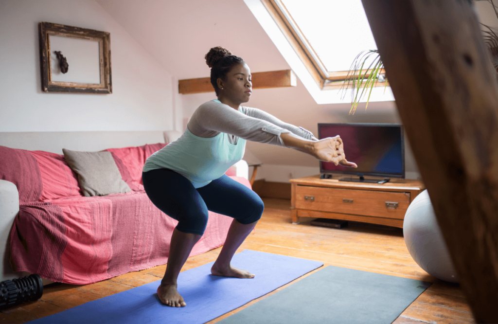 A woman does a squat barefoot at home