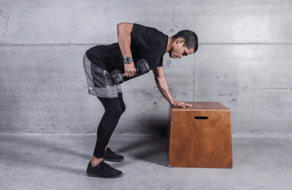 A man does dumbbell rows on a table