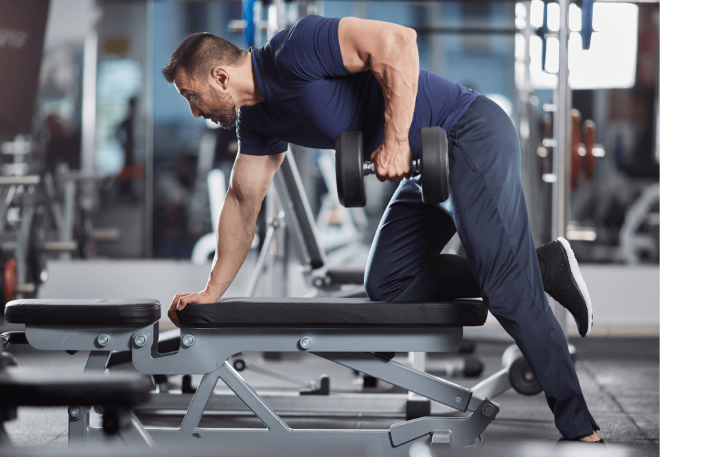 Muscular man does dumbbell rows in a gym