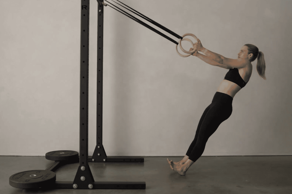 Fit woman doing pull ups with gymnastic rings at the gym or at