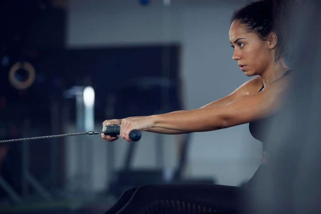 a woman doing a rowing exercise at home