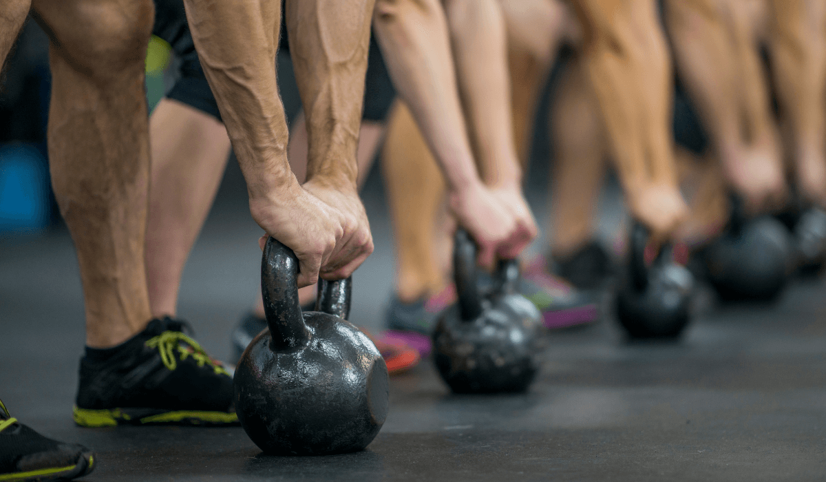 Athletes doing kettlebell leg exercises at the gym