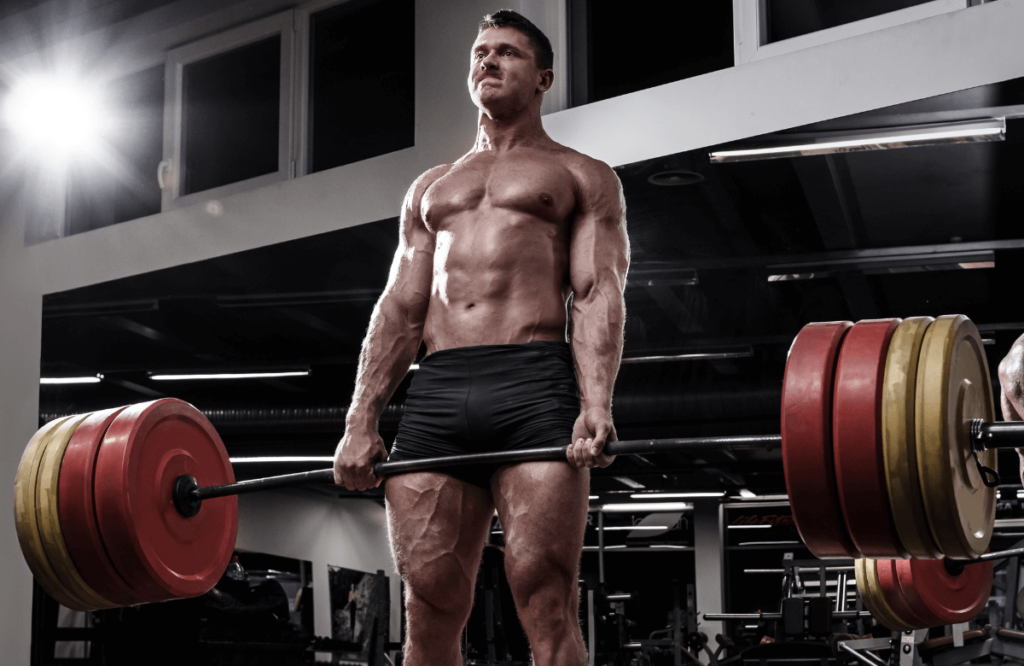 Un hombre fuerte en el gimnasio levantando su propio peso medio de peso muerto