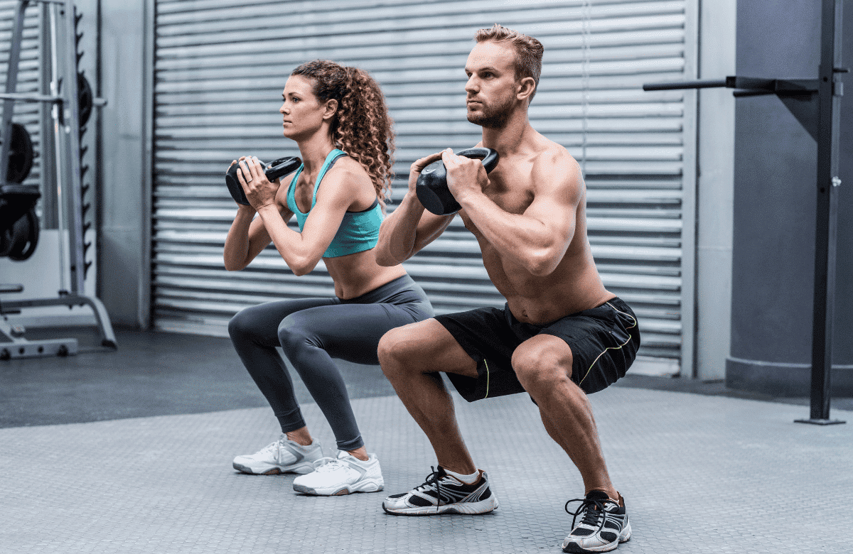 Un homme et une femme réalisent un squat kettlebell dans une salle de sport