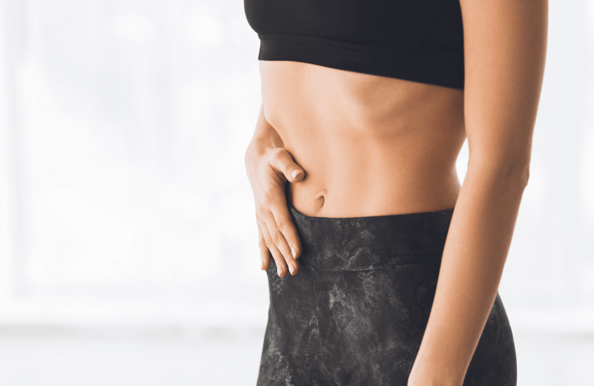 Un femme réalise l'exercice du stomach vacuum pour muscler son transverse