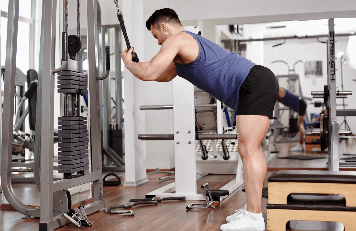 A muscular man performing cable arm workouts at the gym