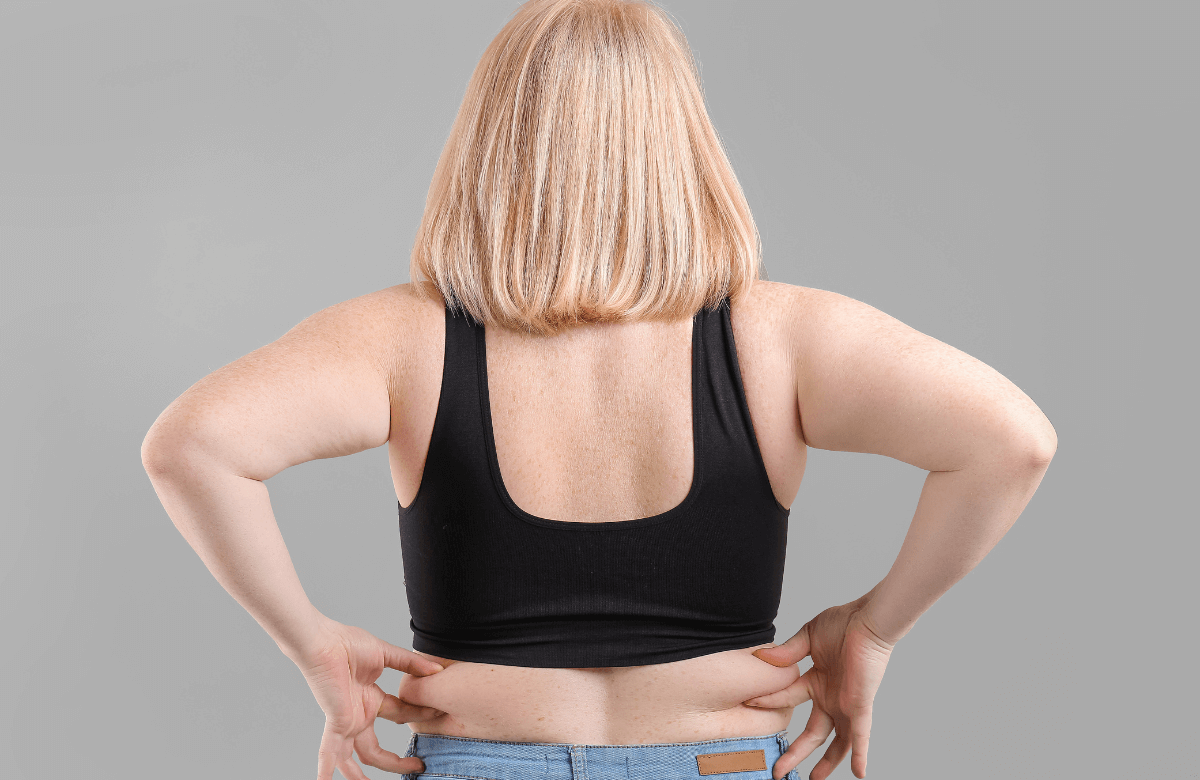 A fat woman holds her love handles